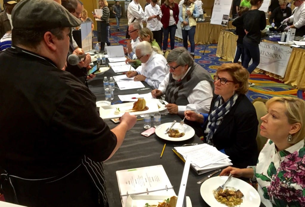 A cooking team chef presents a dish to the food judging panel at the 2016 Cast Iron Cook-Off in Charleston WV.